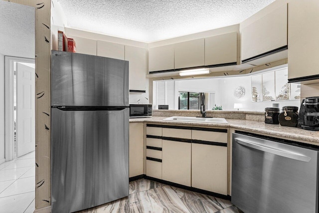 10 Via De Casas Sur Unit 104, Boynton Beach, FL 33426 - kitchen with appliances with stainless steel finishes, a sink, a textured ceiling, cream cabinets, and light countertops