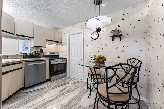 10 Via De Casas Sur Unit 104, Boynton Beach, FL 33426 - kitchen with stainless steel appliances, under cabinet range hood, light marble finish flooring, a textured ceiling, and hanging light fixtures
