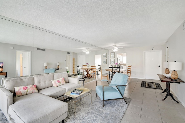 living room with ceiling fan, light tile patterned floors, and a textured ceiling