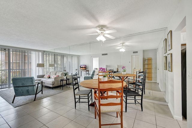 dining room with a wall of windows, ceiling fan, light tile patterned floors, and a textured ceiling