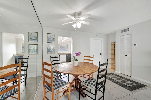 dining space featuring ceiling fan, light tile patterned floors, and a textured ceiling