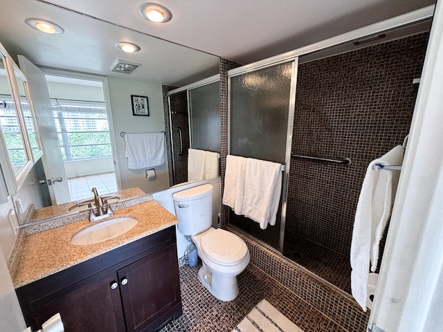 bathroom featuring vanity, toilet, a shower with door, and tile patterned floors