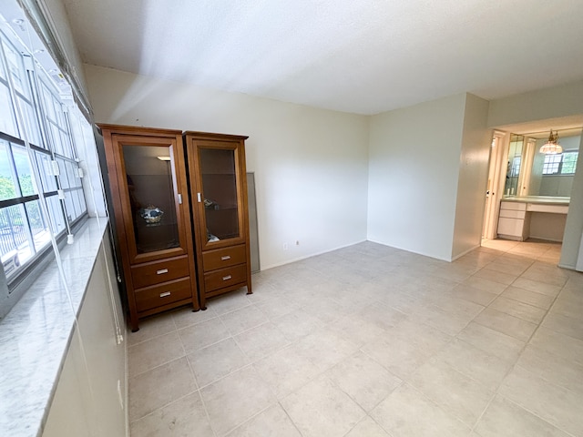 unfurnished bedroom with light tile patterned floors and connected bathroom