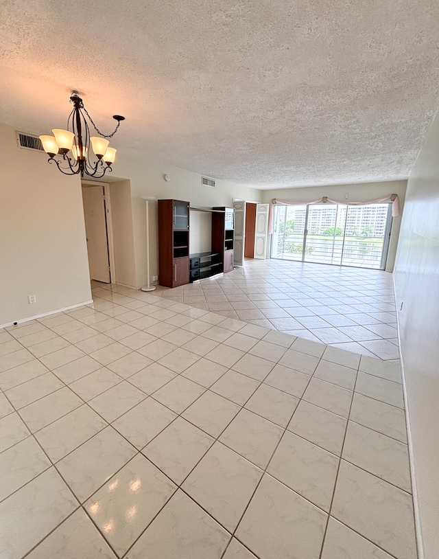 interior space with an inviting chandelier, a textured ceiling, and light tile patterned floors