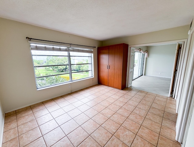 unfurnished room featuring a textured ceiling and light tile patterned flooring