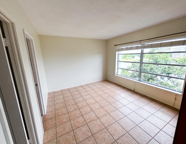 unfurnished room featuring a textured ceiling and light tile patterned floors