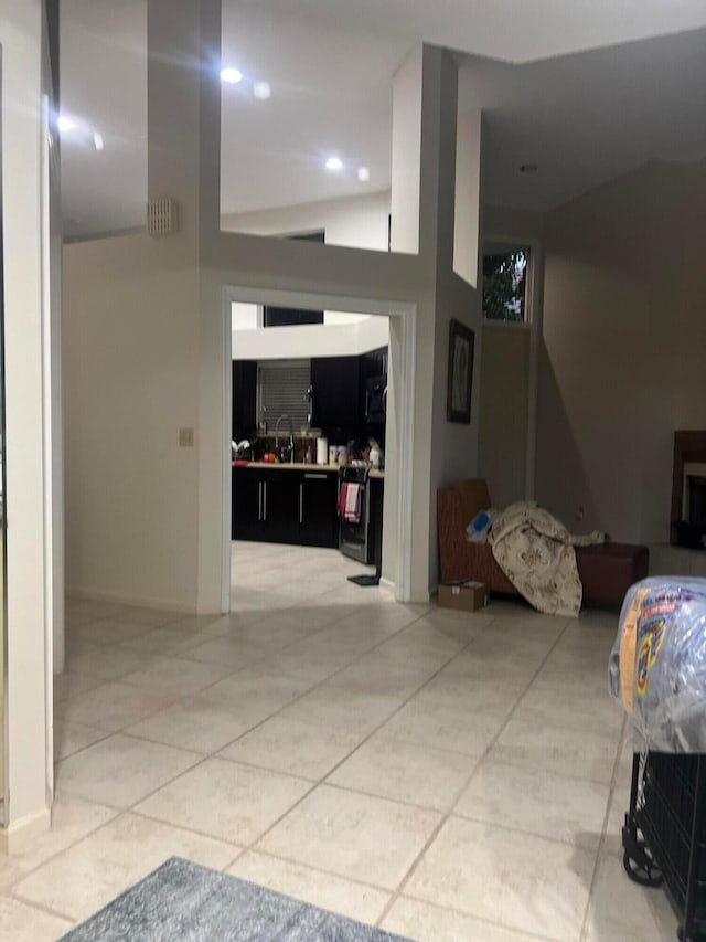 hallway with lofted ceiling, sink, and tile patterned floors