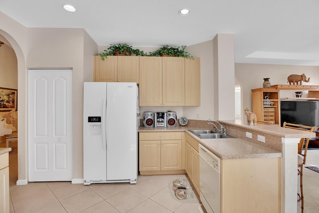 kitchen featuring a breakfast bar area, white appliances, light tile patterned floors, kitchen peninsula, and sink