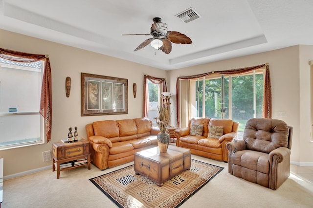 living room with light colored carpet, ceiling fan, and a tray ceiling