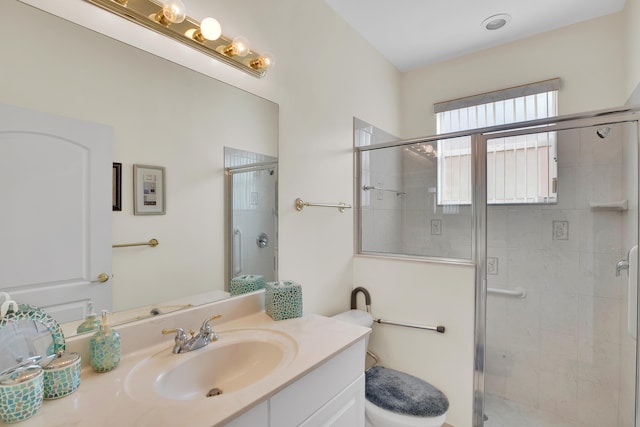 bathroom featuring a shower with door, vanity, and toilet