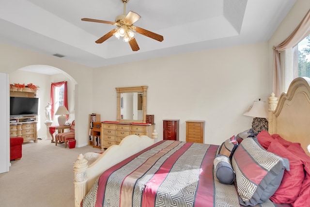 carpeted bedroom featuring ceiling fan and a raised ceiling