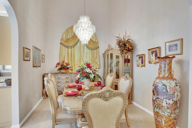 dining space with a high ceiling, an inviting chandelier, and light carpet