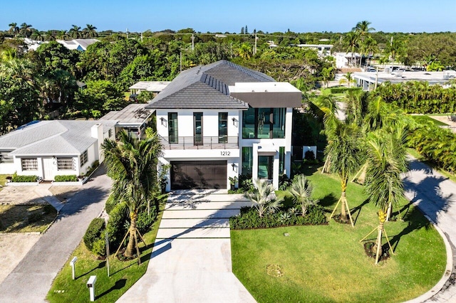 exterior space with a garage, a balcony, and a front yard