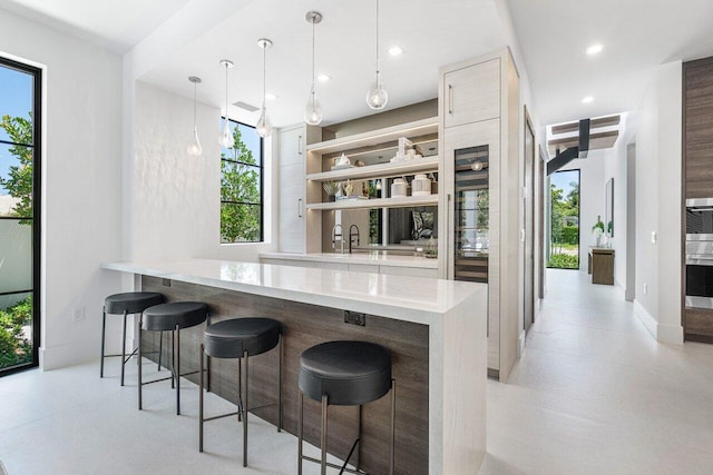 kitchen featuring stainless steel oven, kitchen peninsula, hanging light fixtures, and a breakfast bar area