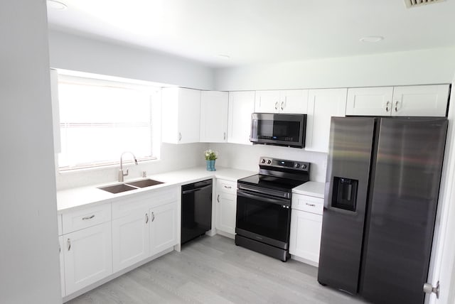 kitchen featuring sink, appliances with stainless steel finishes, white cabinets, and light hardwood / wood-style floors