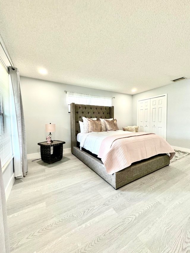 bedroom featuring a textured ceiling, a closet, and light hardwood / wood-style floors