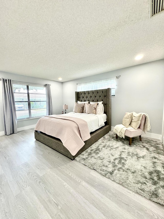 interior space with a textured ceiling and light hardwood / wood-style floors