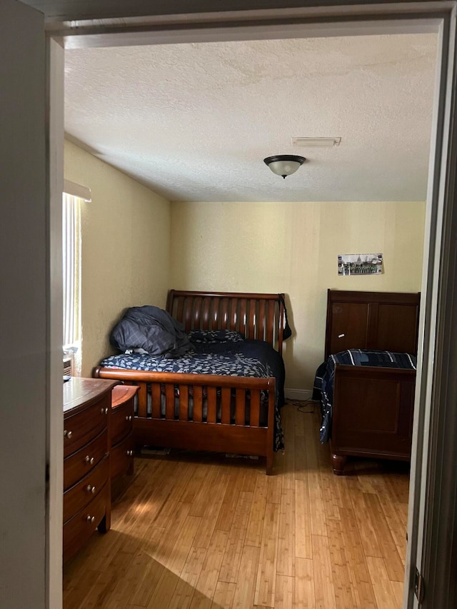 bedroom with a textured ceiling and light hardwood / wood-style flooring