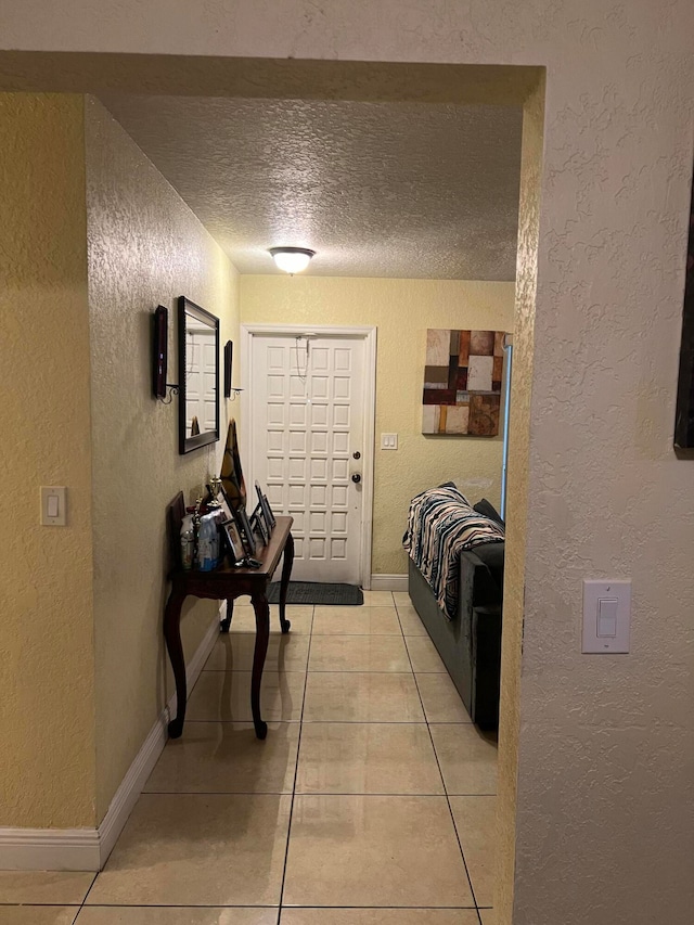 hall featuring light tile patterned flooring and a textured ceiling