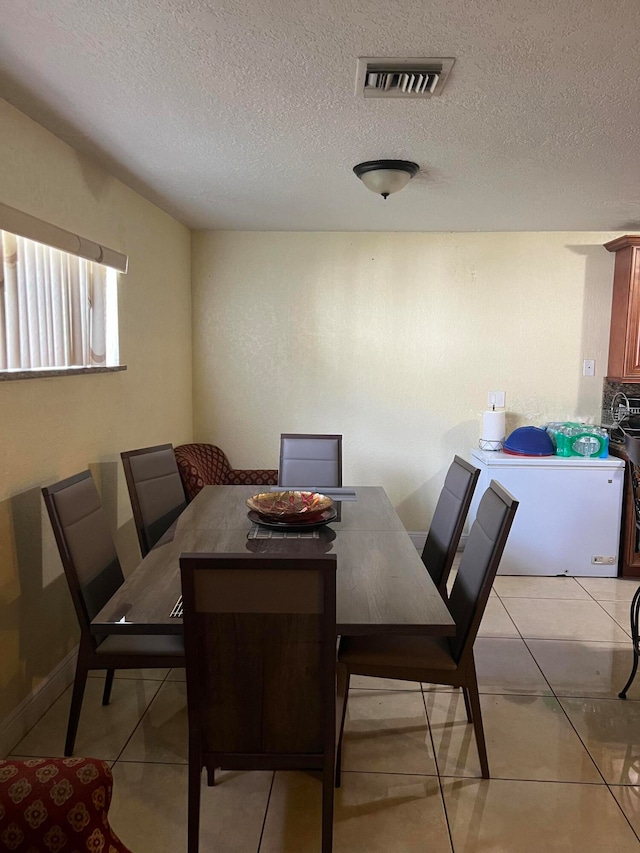 dining room featuring light tile patterned floors and a textured ceiling