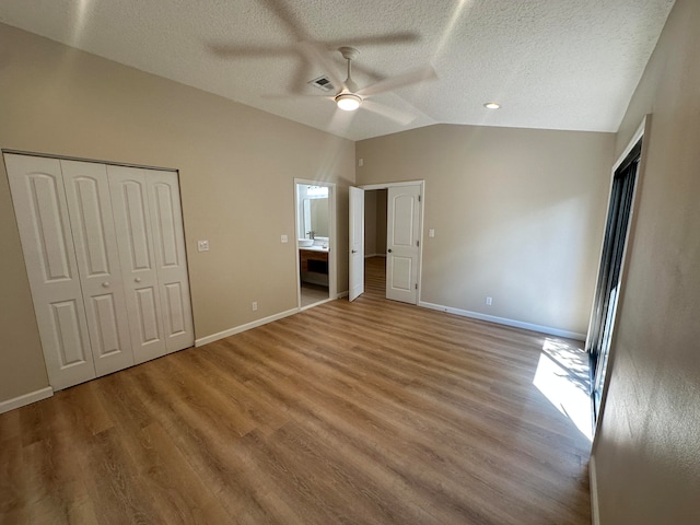 unfurnished bedroom with lofted ceiling, ceiling fan, light hardwood / wood-style floors, and a textured ceiling