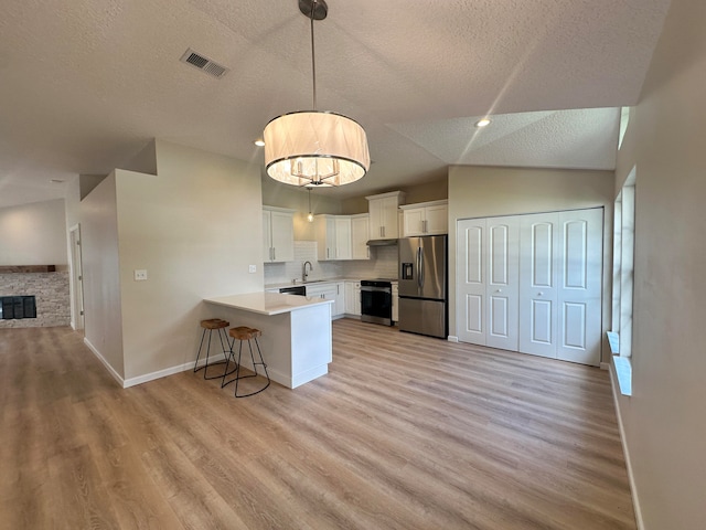 kitchen with white cabinets, appliances with stainless steel finishes, sink, kitchen peninsula, and a kitchen breakfast bar