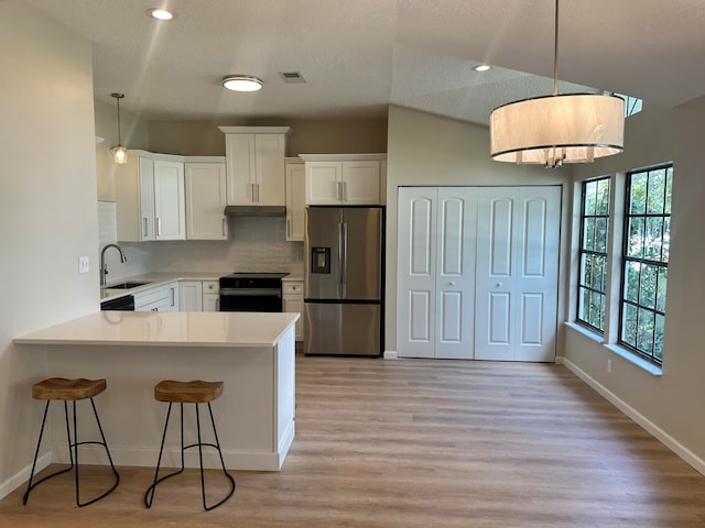 kitchen with white cabinets, stainless steel fridge, black range with electric stovetop, and kitchen peninsula