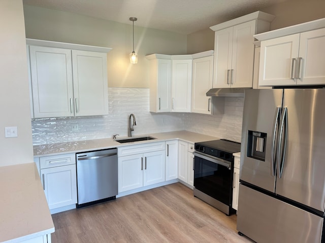 kitchen with appliances with stainless steel finishes, pendant lighting, white cabinetry, and sink