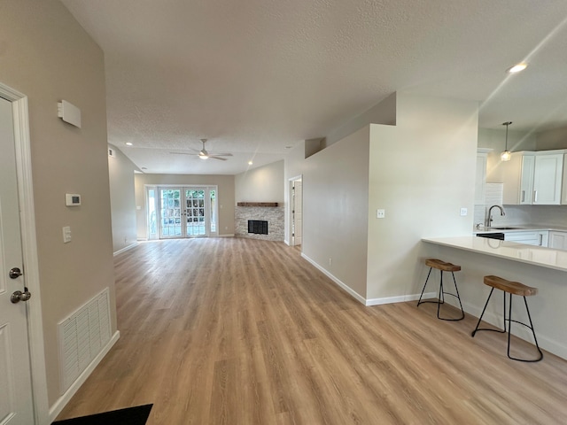 living room featuring light wood-type flooring, ceiling fan, a textured ceiling, and sink