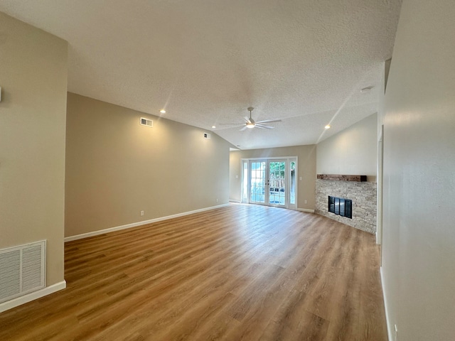 unfurnished living room featuring a fireplace, light wood-type flooring, a textured ceiling, ceiling fan, and vaulted ceiling