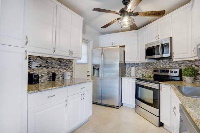 kitchen with appliances with stainless steel finishes, white cabinets, ceiling fan, and backsplash