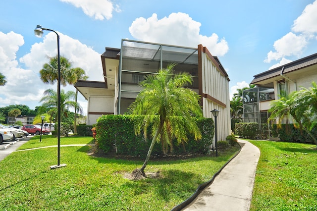 view of side of home featuring a lanai and a lawn