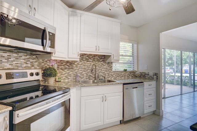 kitchen with decorative backsplash, appliances with stainless steel finishes, white cabinetry, light tile patterned flooring, and sink