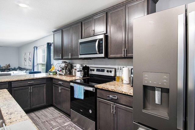 kitchen featuring dark brown cabinetry, appliances with stainless steel finishes, and light hardwood / wood-style flooring