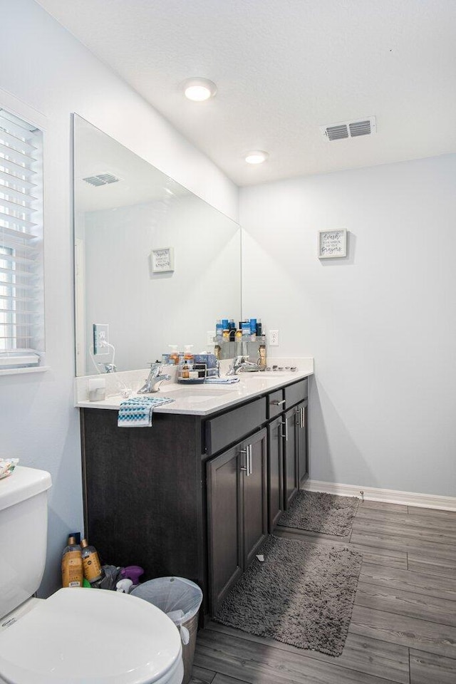 bathroom with wood-type flooring, vanity, and toilet