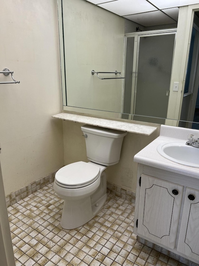 bathroom with a shower with door, tile patterned floors, toilet, vanity, and a paneled ceiling