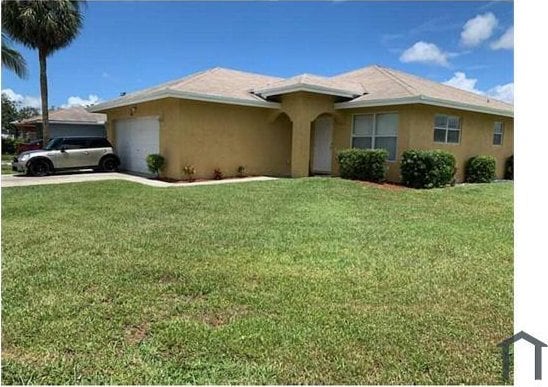 single story home featuring a garage and a front lawn