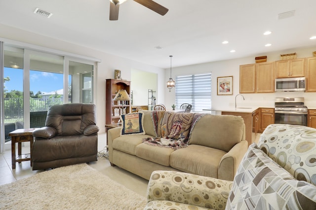 tiled living room with ceiling fan and sink