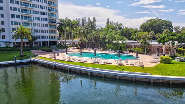 view of pool featuring a water view, a yard, and a patio