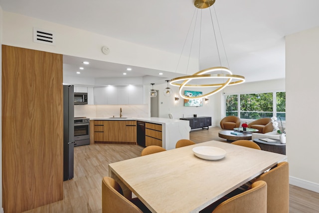 dining room featuring light hardwood / wood-style floors, a notable chandelier, and sink