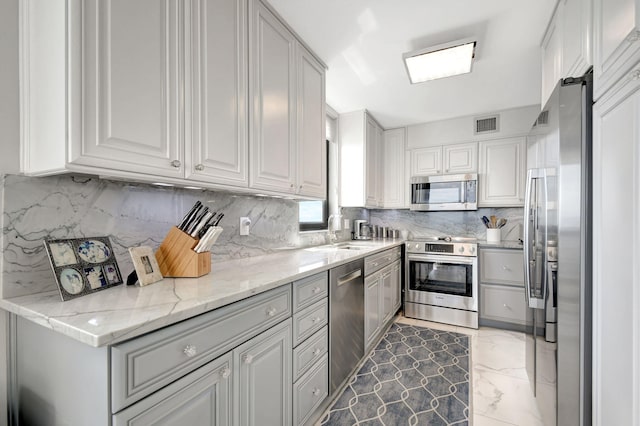 kitchen featuring tasteful backsplash, sink, stainless steel appliances, and light stone countertops