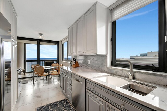 kitchen with light stone countertops, dishwasher, decorative backsplash, and a healthy amount of sunlight