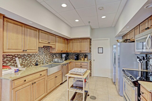 kitchen featuring light tile patterned floors, stainless steel appliances, sink, and light stone countertops