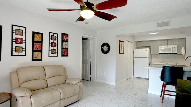 living room with a textured ceiling and ceiling fan