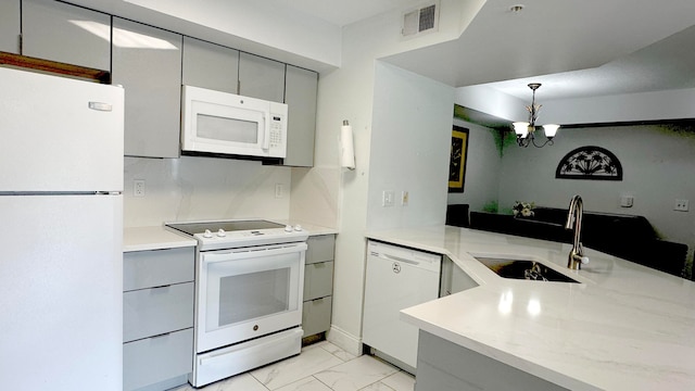 kitchen featuring white appliances, a chandelier, sink, hanging light fixtures, and gray cabinetry