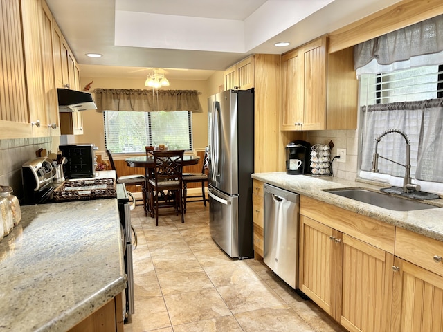 kitchen with tasteful backsplash, stainless steel appliances, light brown cabinetry, sink, and a raised ceiling