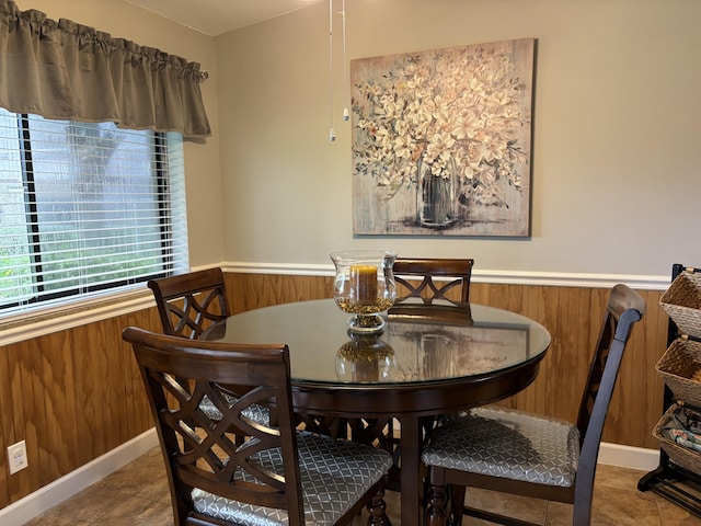 dining space featuring wood walls and tile patterned floors