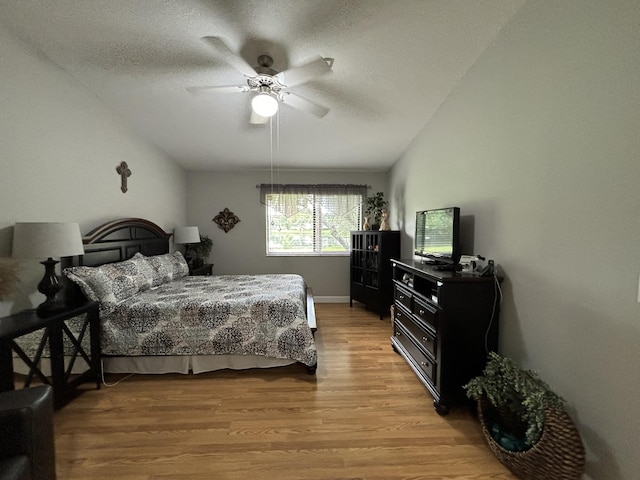 bedroom featuring a textured ceiling, lofted ceiling, ceiling fan, and light hardwood / wood-style floors