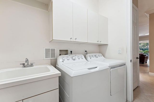 clothes washing area featuring light tile patterned floors, sink, cabinets, and washer and dryer