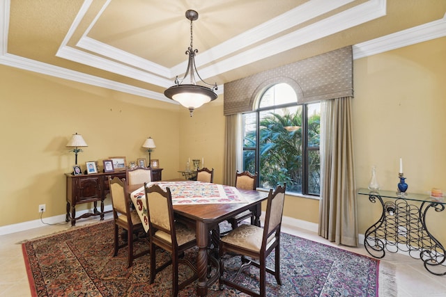 tiled dining room with a raised ceiling and crown molding